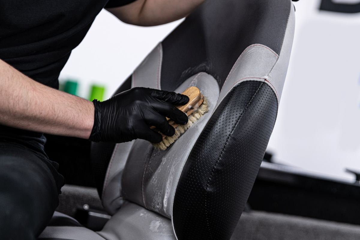 Technician hand-scrubbing a seat cushion with a detail brush